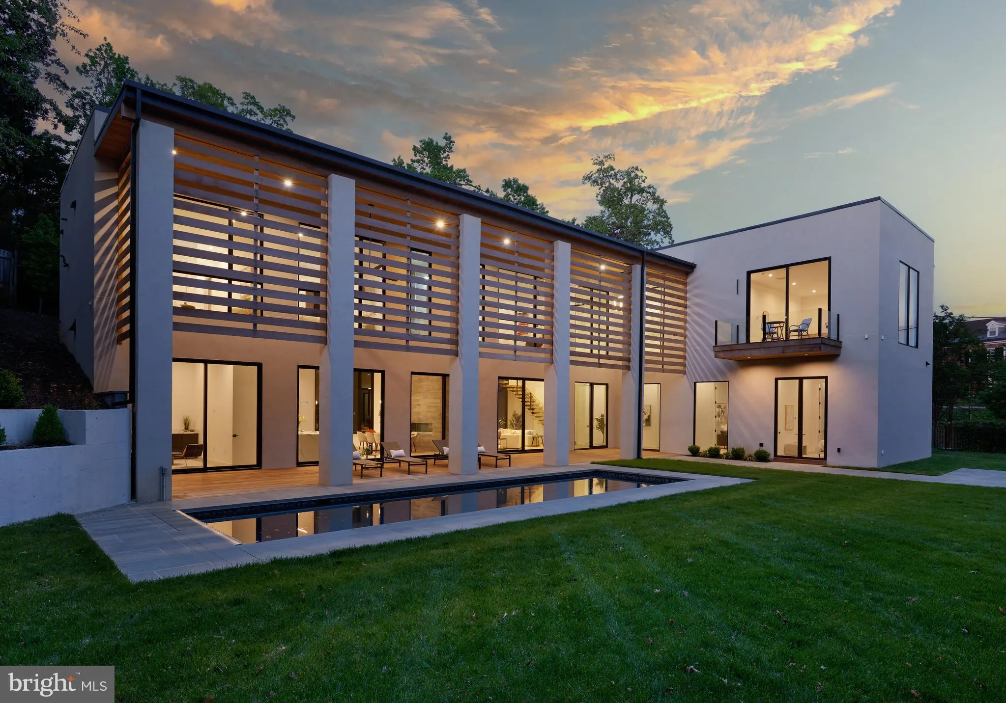 Rear exterior of a Colonial custom build at 2800 32nd St NW, DC, with lap pool and wood-slat screening at dusk