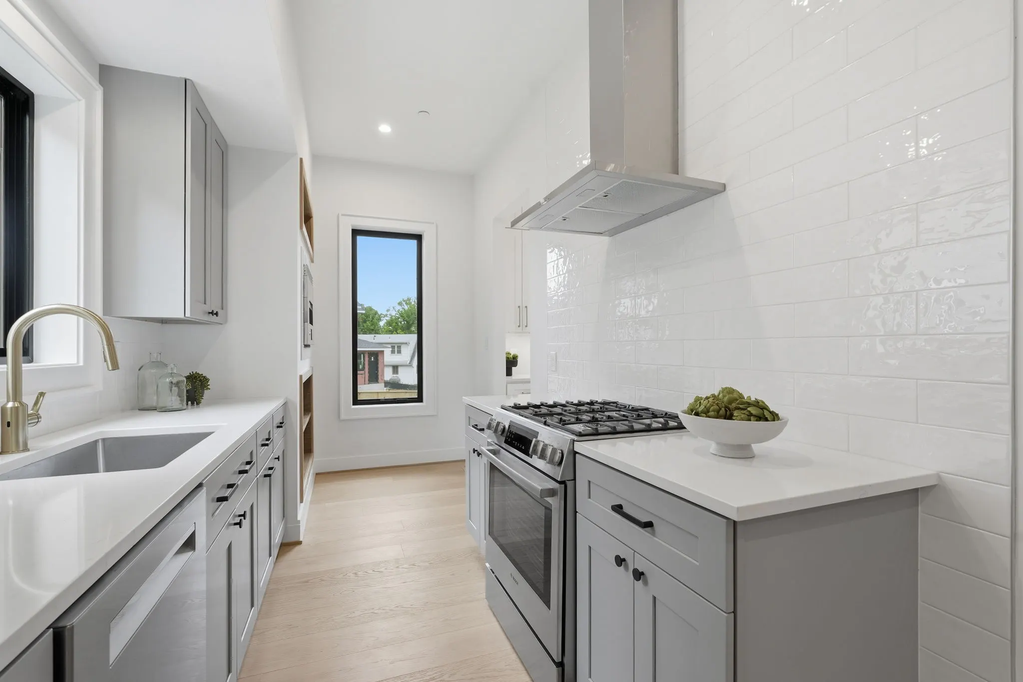 Kitchen with white waterfall island, white oak cabinetry, and pendant lighting