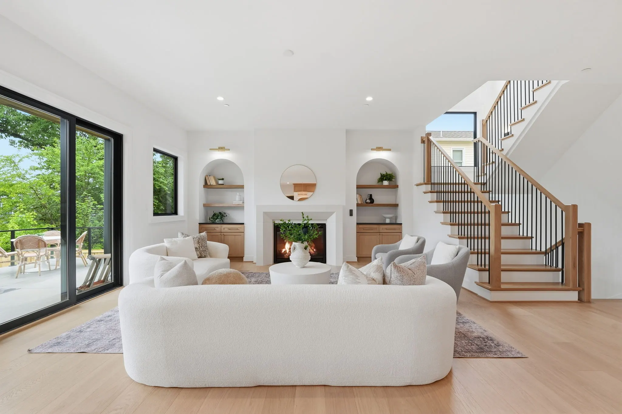 Great room with white oak floors, arched built-ins, and oak-railed staircase